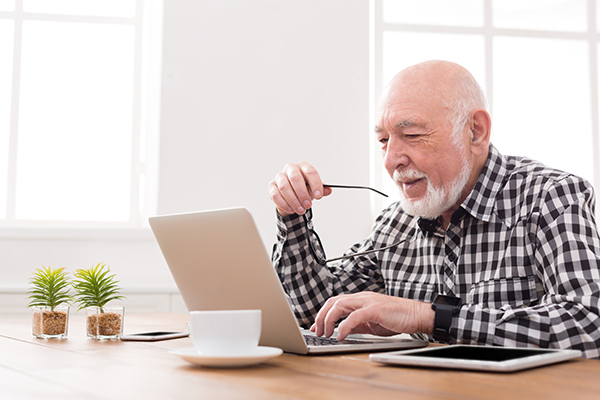 Smiling senior man using laptop.